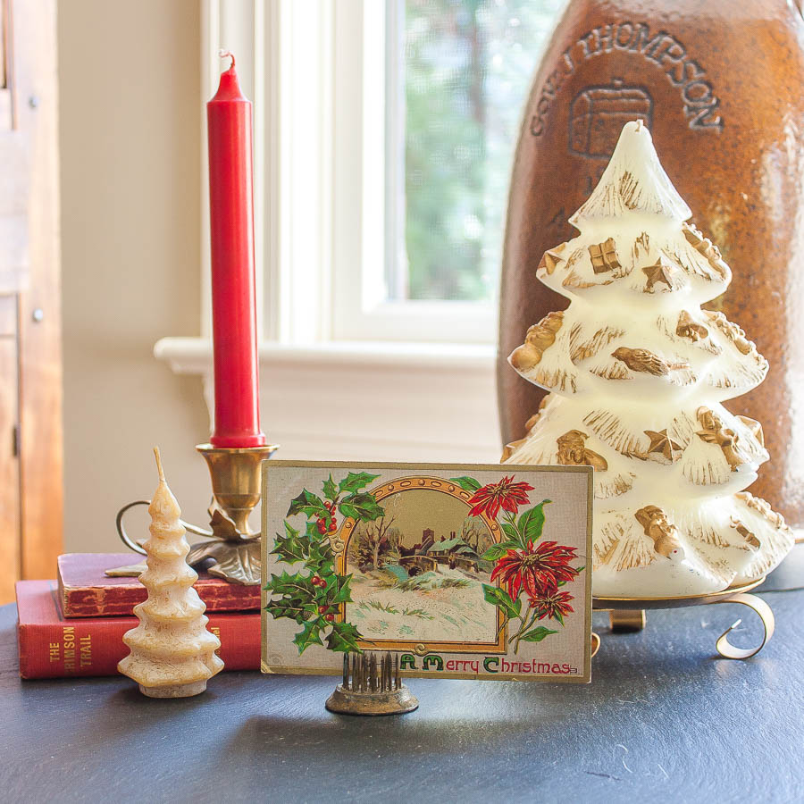 Family Room decorated for Christmas with vintage. 1911 Christmas postcard, vintage candle Christmas trees, and vintage books with red covers.