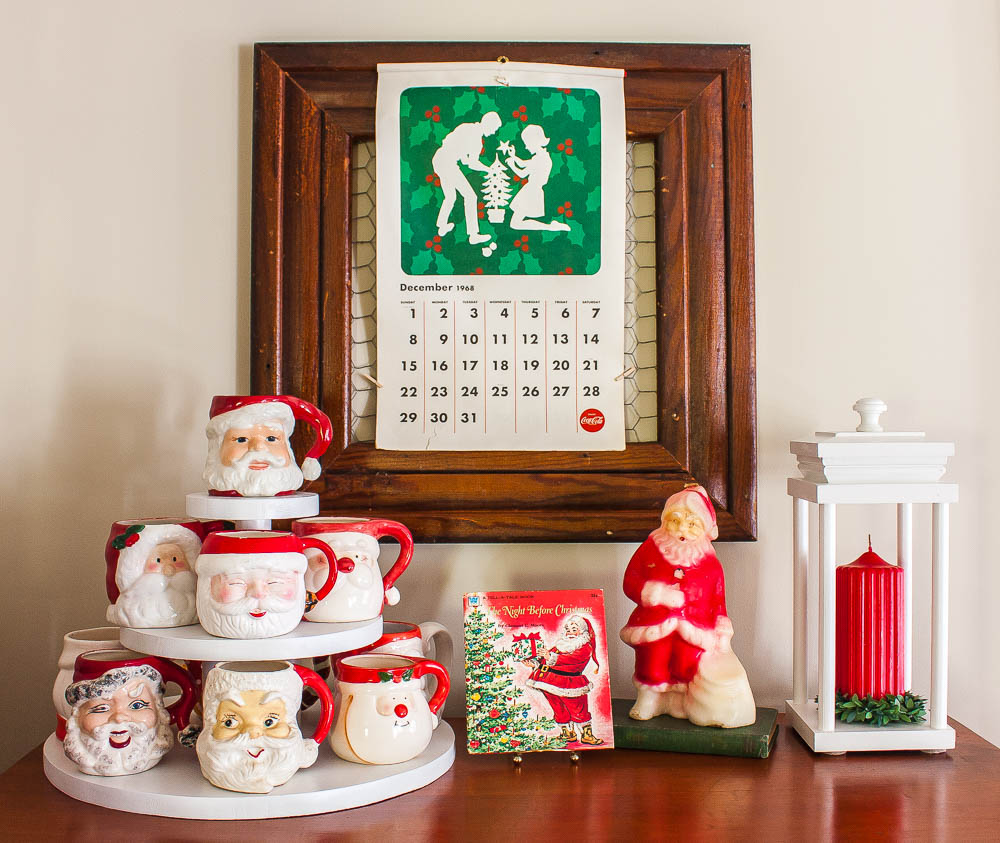 1968 Coca-Cola calendar, collection of vintage Santa mugs, 1976 The Night Before Christmas Book, vintage Santa candle, and a lantern holding a red candle