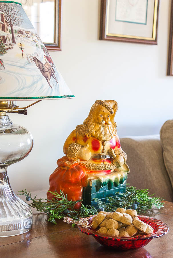 Antique lamp with a Christmas lamp shade with holes that illuminate the scene on it, vintage Santa bank, and a reindeer bowl filled with dog treats