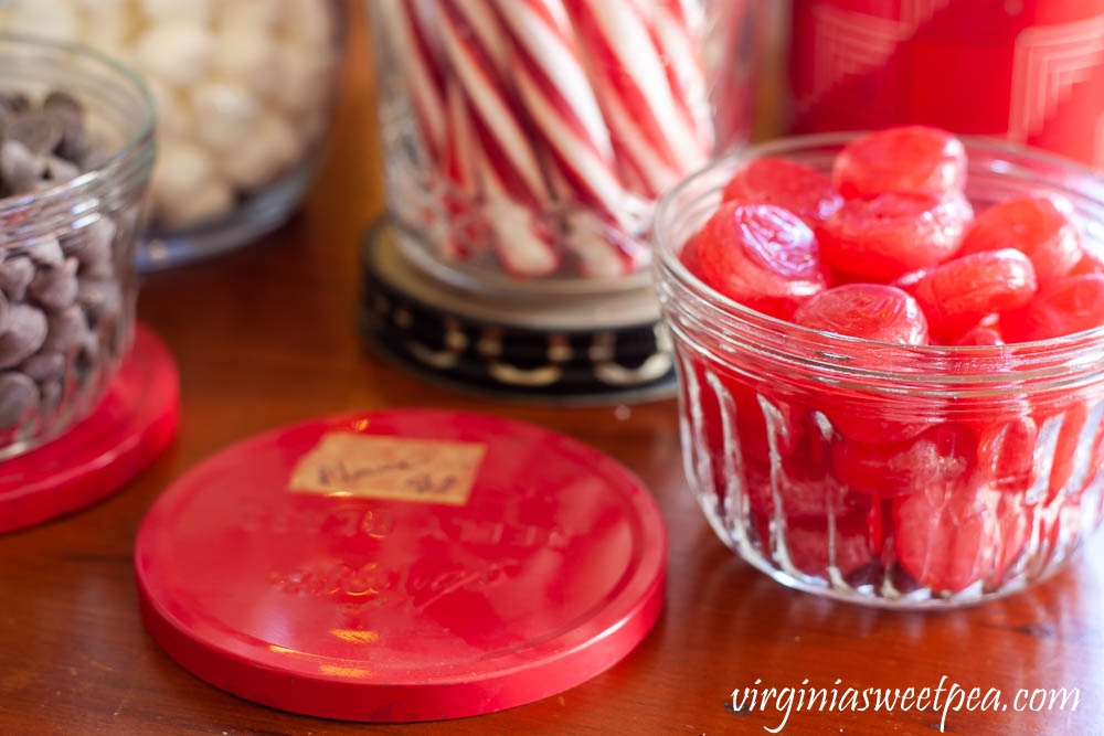 Chocolate chips and cinnamon candies served in vintage jelly jars on a hot chocolate bar