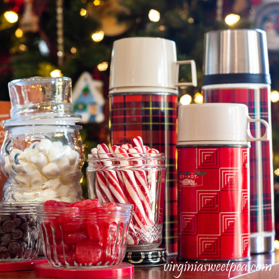 Hot Chocolate Bar with Vintage - Vintage jelly jars holding chocolate chips and cinnamon candy, a Nescafe jar holding peppermint sticks, and a trio thermoses.