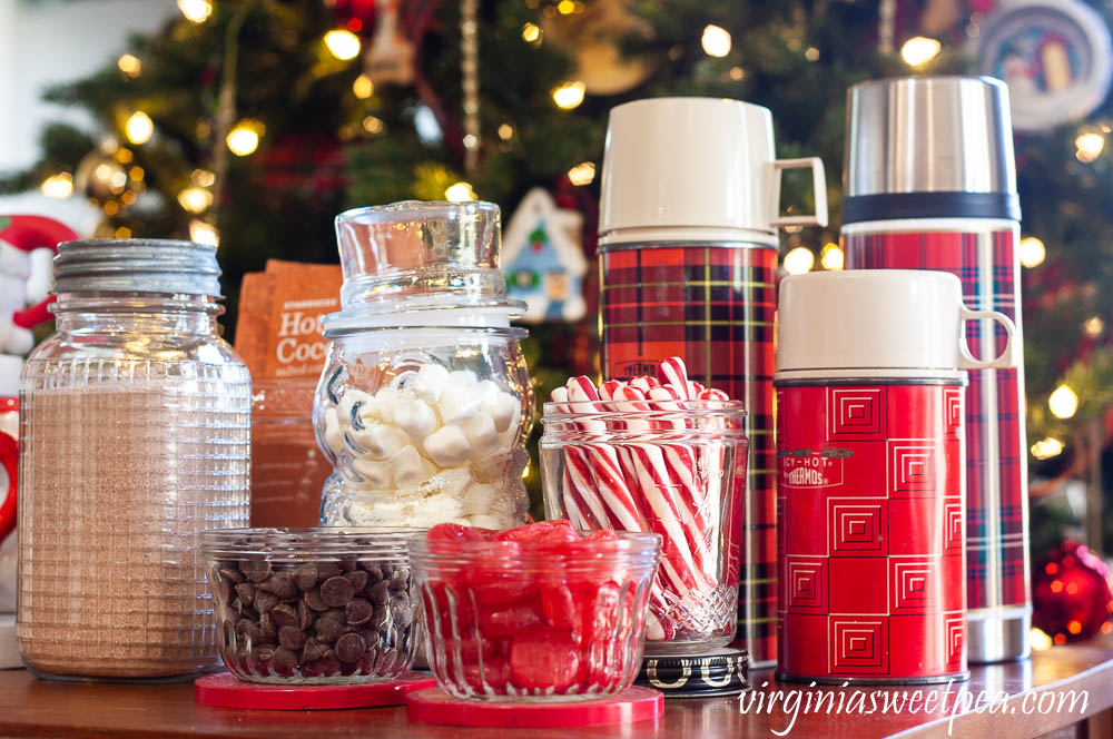 Hot Chocolate Bar with Vintage - Vintage jelly jars holding chocolate chips and cinnamon candy, a Nescafe jar holding peppermint sticks, and a trio thermoses.