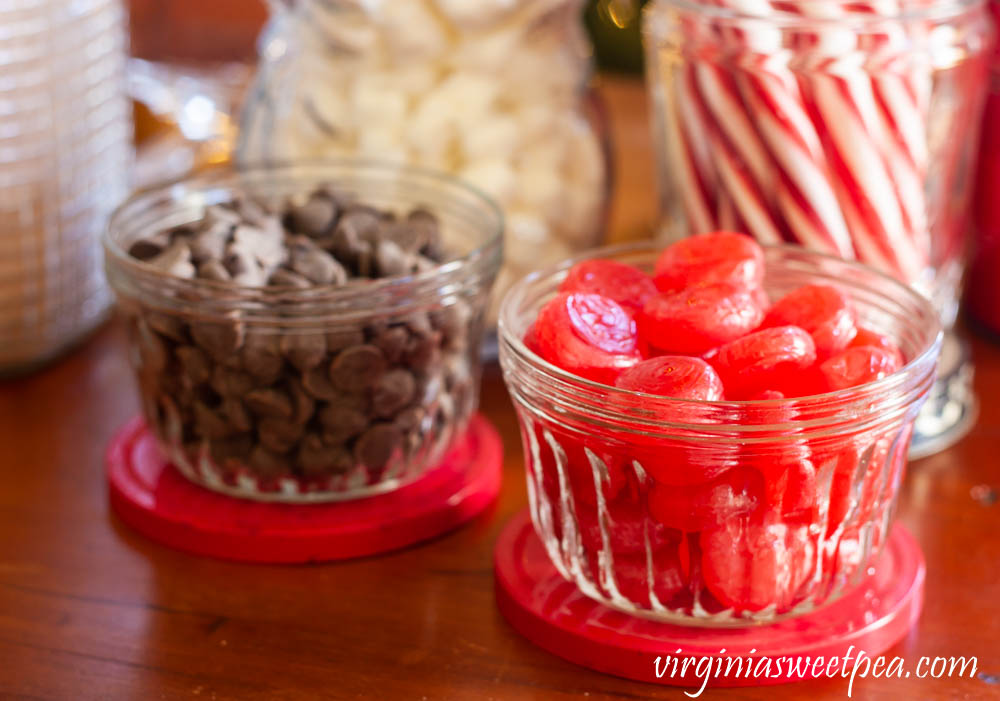 Chocolate chips and cinnamon candies served in vintage jelly jars on a hot chocolate bar