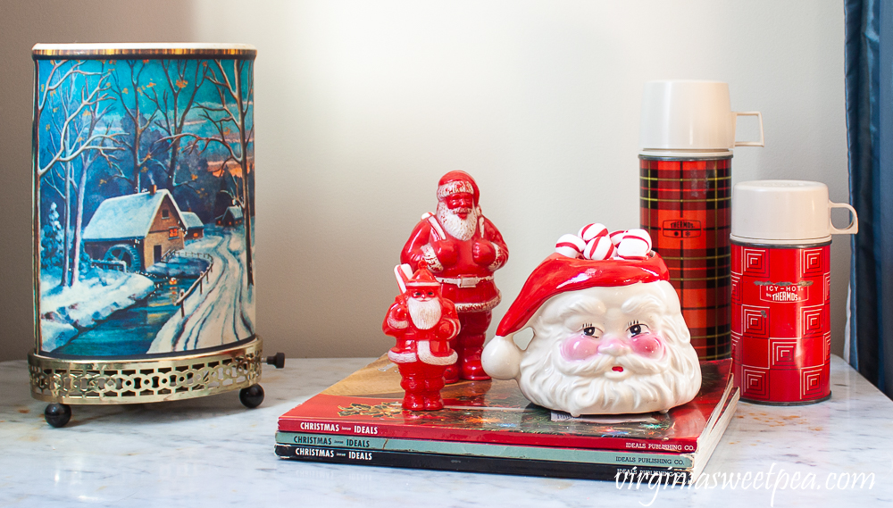 Vintage winter scene Econolite motion lamp, Christmas Ideals books from the 1960's, vintage plastic Santa candy holders, vintage Santa mug, and two vintage thermoses