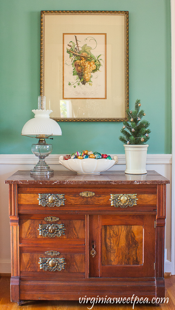 A Very Vintage Christmas in the Dining Room - Antique chest decorated for Christmas with vintage ornaments in a McCoy dish.