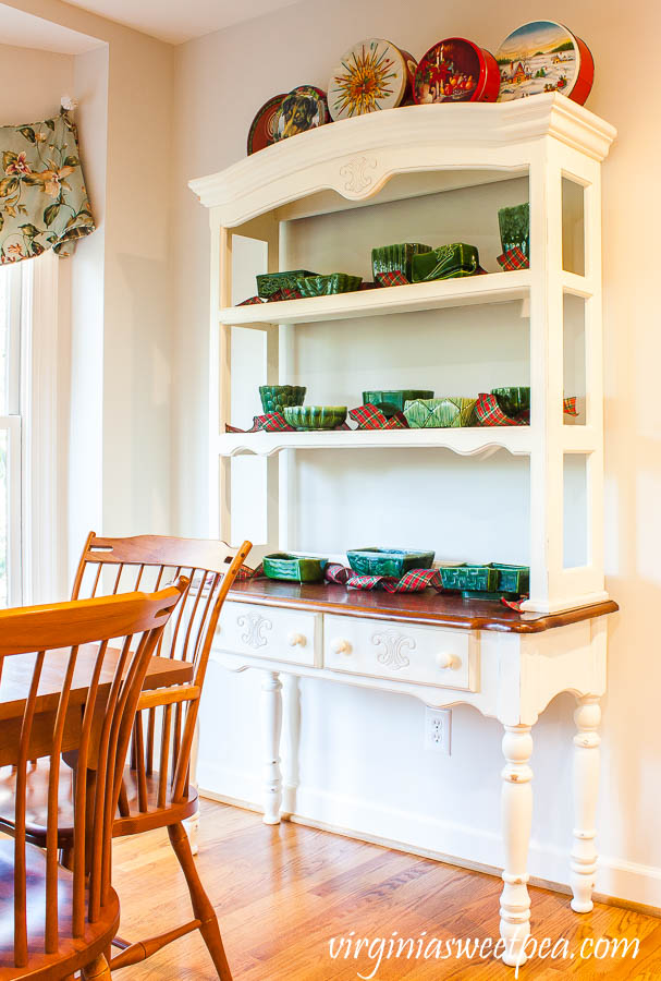 Farmhouse Style Shelves Decorated for Christmas with vintage tins, vintage green pottery, and plaid ribbon.