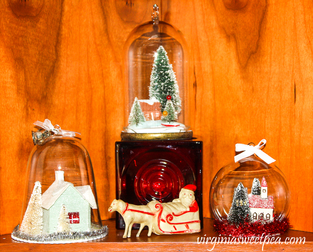Kitchen shelf decorated for Christmas with a vintage Santa and reindeer, red Blenko candle, and vintage-look ornaments