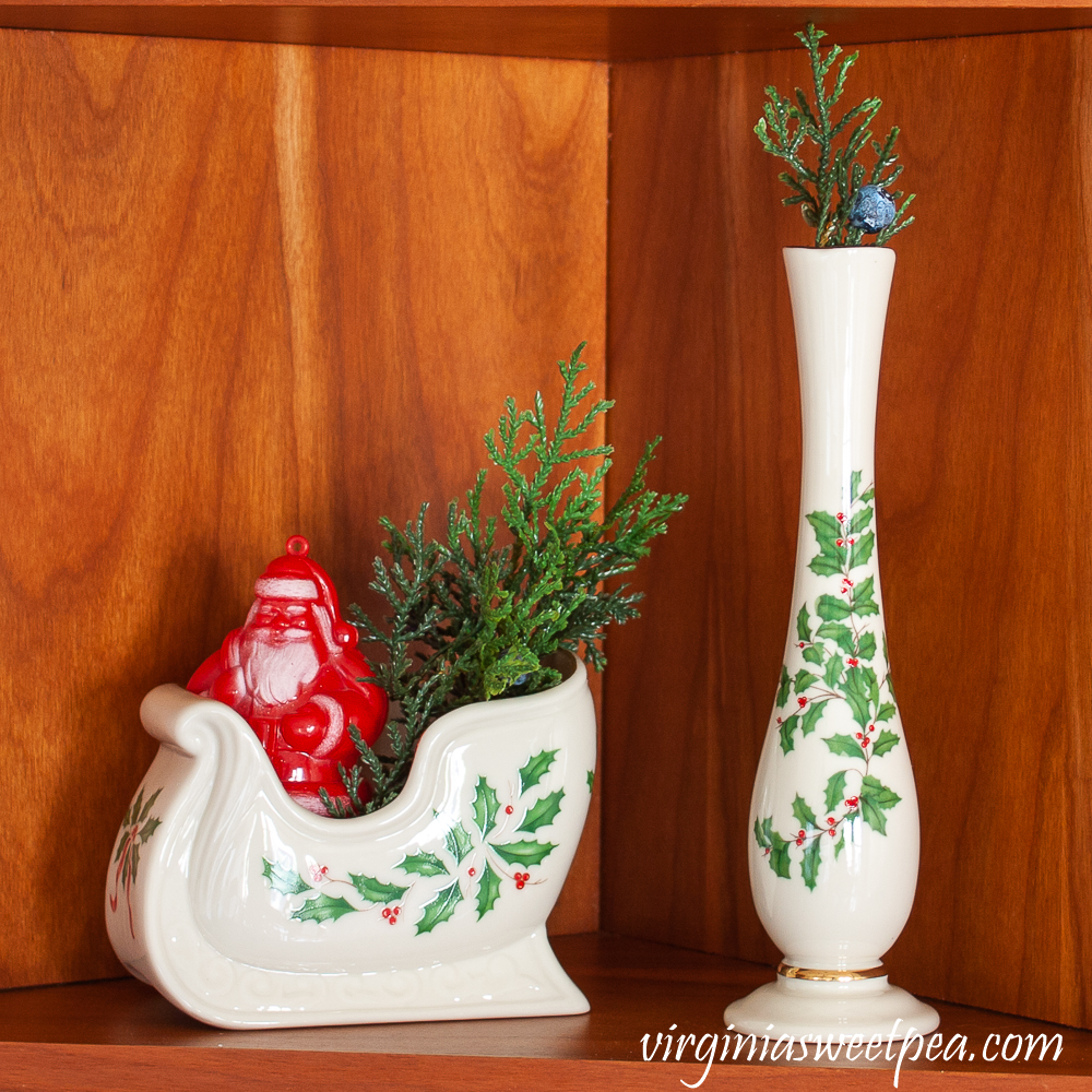 Kitchen shelf decorated for Christmas with Lenox Holiday pieces and a vintage Santa candy container.