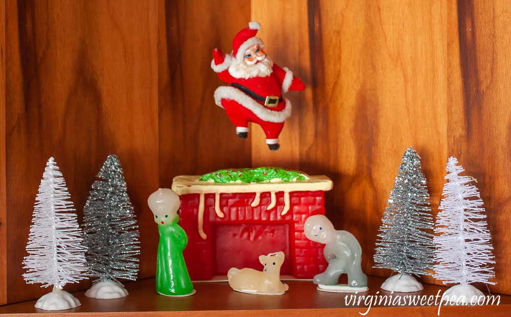 Kitchen shelves decorated for Christmas with vintage style candles from The Vermont Country Store, a vintage Santa, and bottlebrush trees.