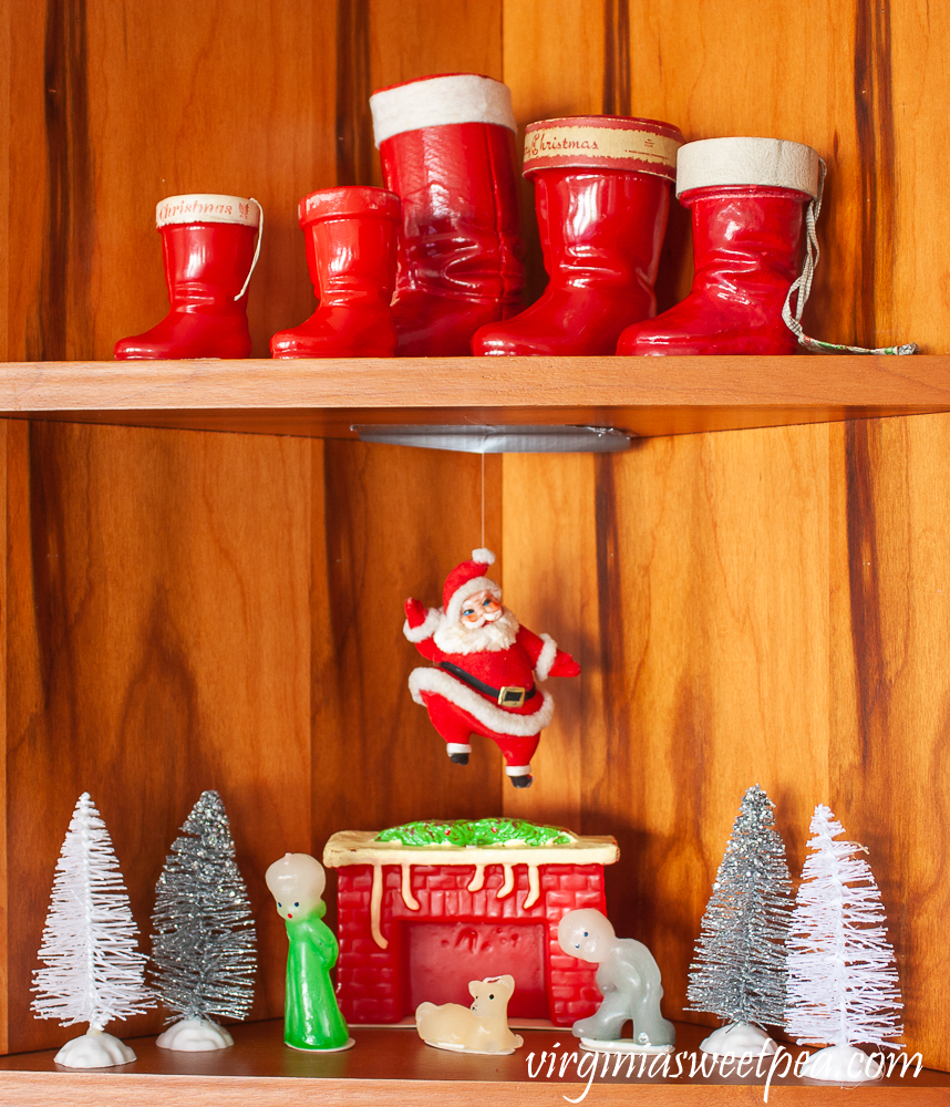 Kitchen shelves decorated for Christmas with vintage Santa boots, vintage style candles from The Vermont Country Store, a vintage Santa, and bottlebrush trees.