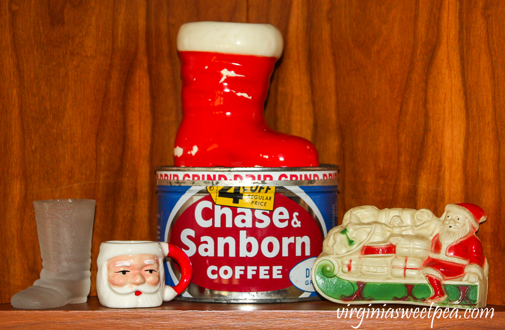 Kitchen shelf decorated for Christmas with a Chase and Sanborn coffee can, vintage celluloid Santa, vintage Santa boots, and a small Santa mug