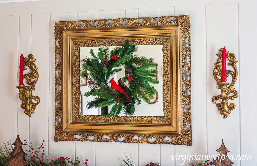 Gold antique mirror with a Christmas wreath and two vintage gold candle holders.