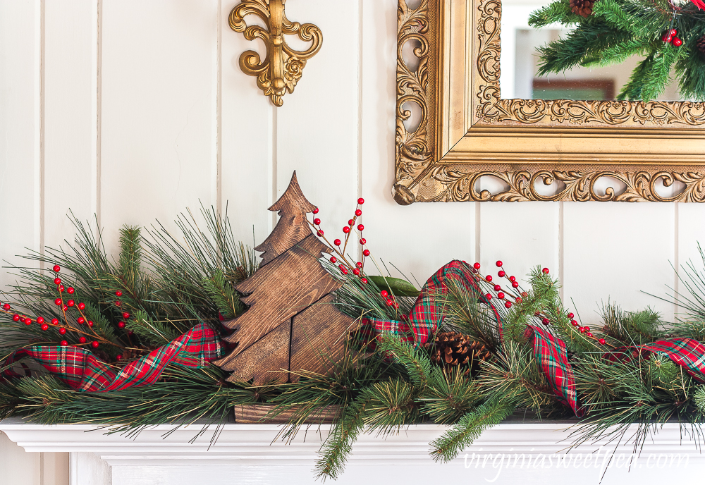 DIY Patchwork Wooden Christmas Trees on a Mantel with a garland, plaid ribbon, and faux red berries.
