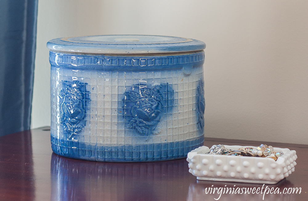 Blue and white antique crock with lid and a milk glass ashtray filled with vintage jewelry.