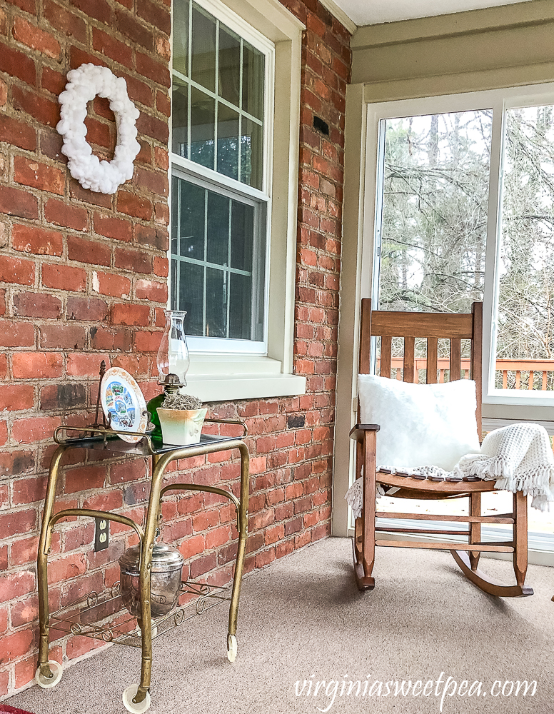 Easy DIY Pom Pom Wreath Displayed on an enclosed porch with brick walls