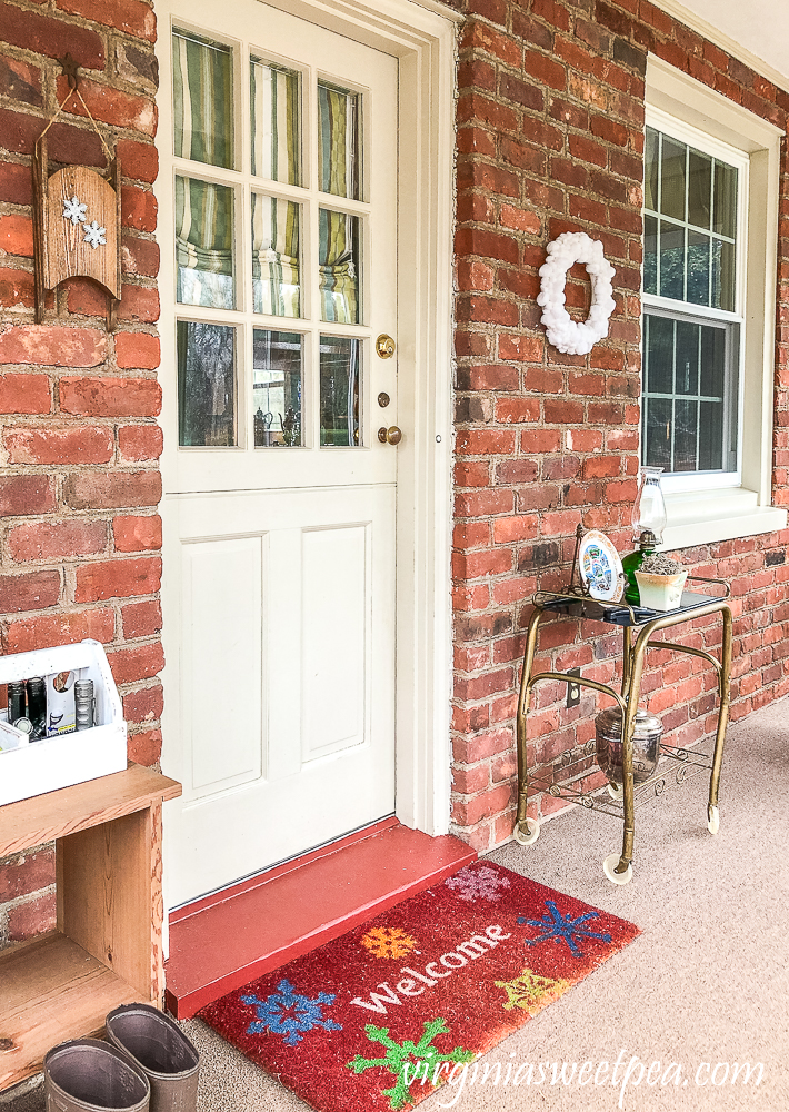 Easy DIY Pom Pom Wreath Displayed on an enclosed porch with brick walls