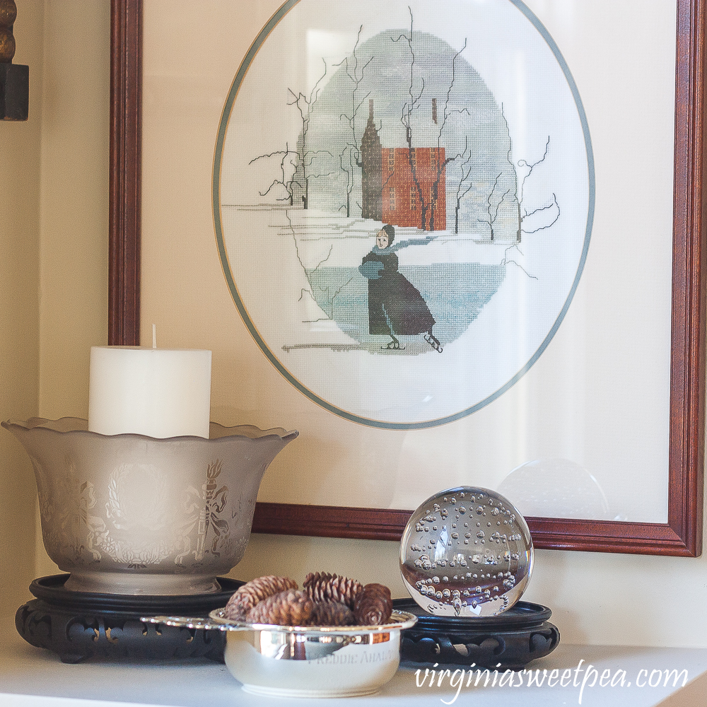 Silver child's porridge bowl, antique glass lamp shade, glass ball with bubbles in the glass, P. Buckley Moss cross stitch