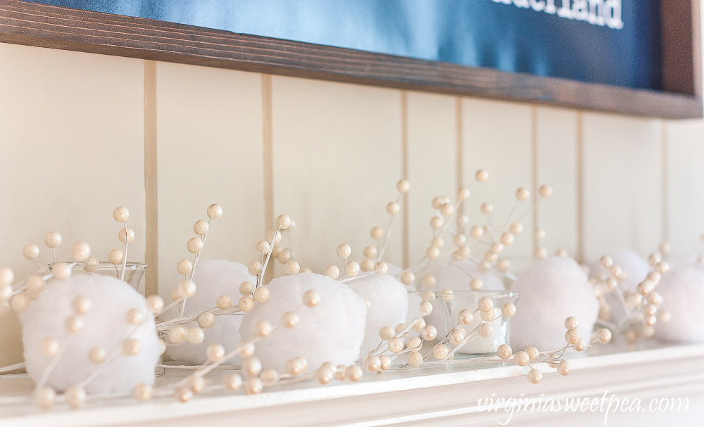 Winter mantel with "Walking in a Winter Wonderland" sign, snowballs, and white berries.