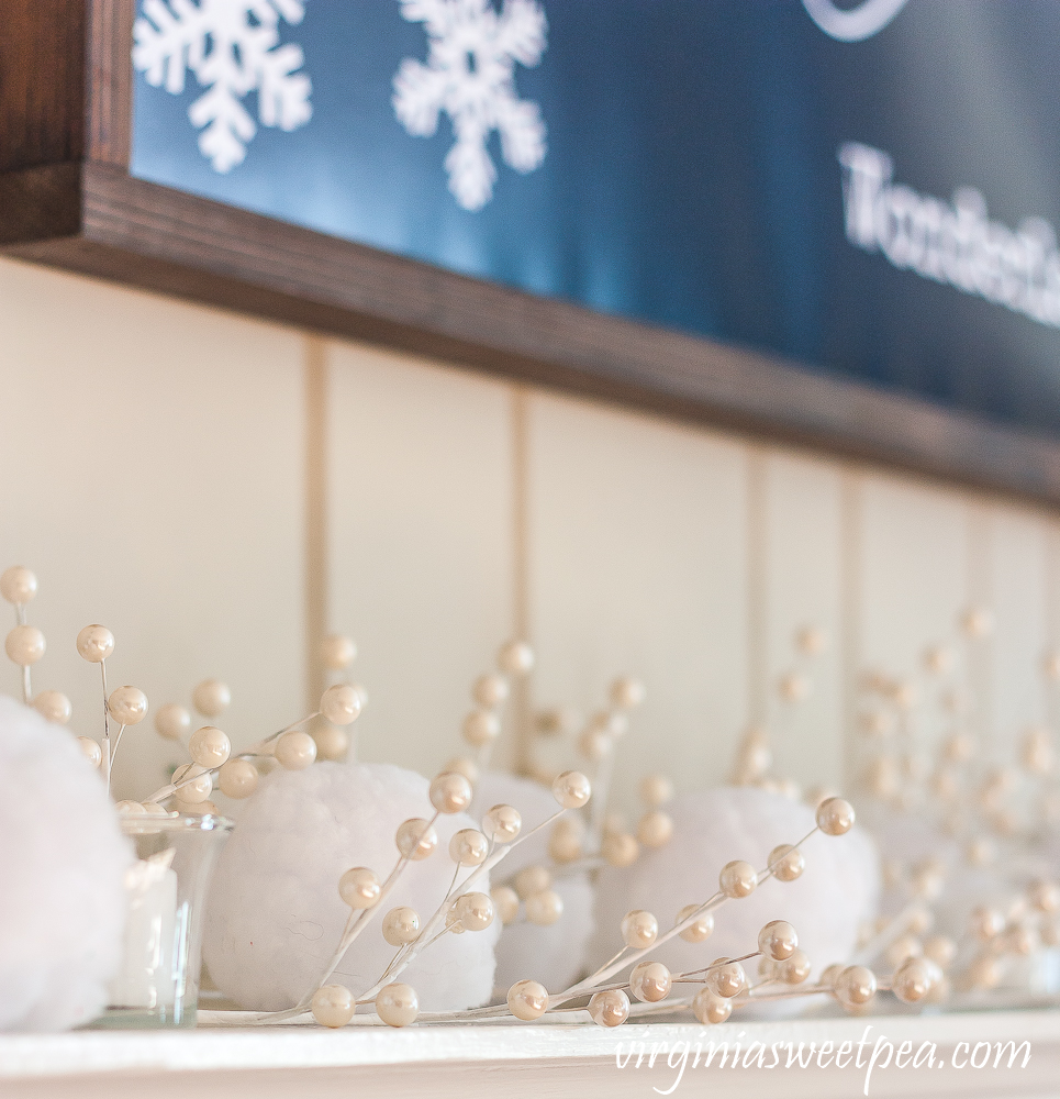 Winter mantel with "Walking in a Winter Wonderland" sign, snowballs, and white berries.