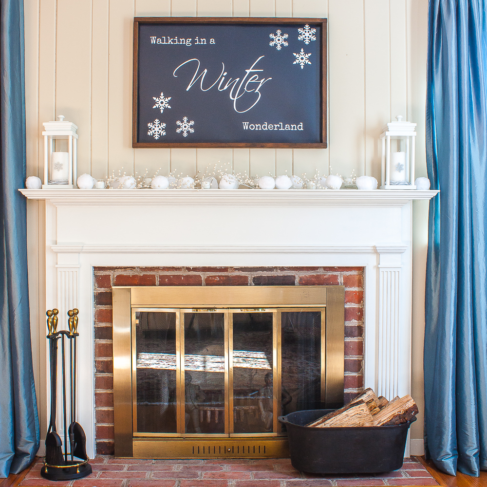 Winter mantel with "Walking in a Winter Wonderland" sign, snowballs, lanterns, and white berries.