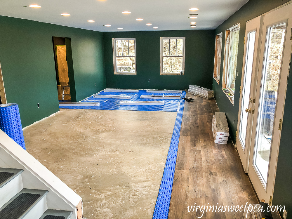 Basement with walls Painted with Sherwin Williams Emerald Paint in Rock Garden and floor installation with Mohawk Crest Loft in Prairie Oak