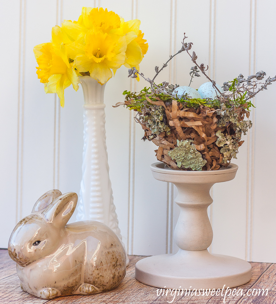 Spring vignette with rabbit, daffodils in a milk glass vase, and a nest.