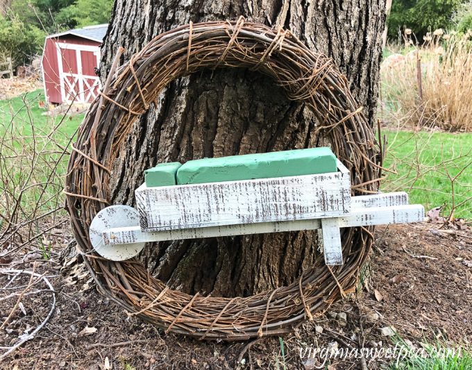 Grapevine wreath with a wheelbarrow wired to it