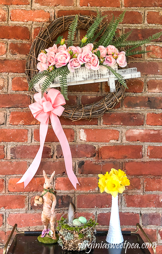 Spring wreath with a wheelbarrow filled with flowers.