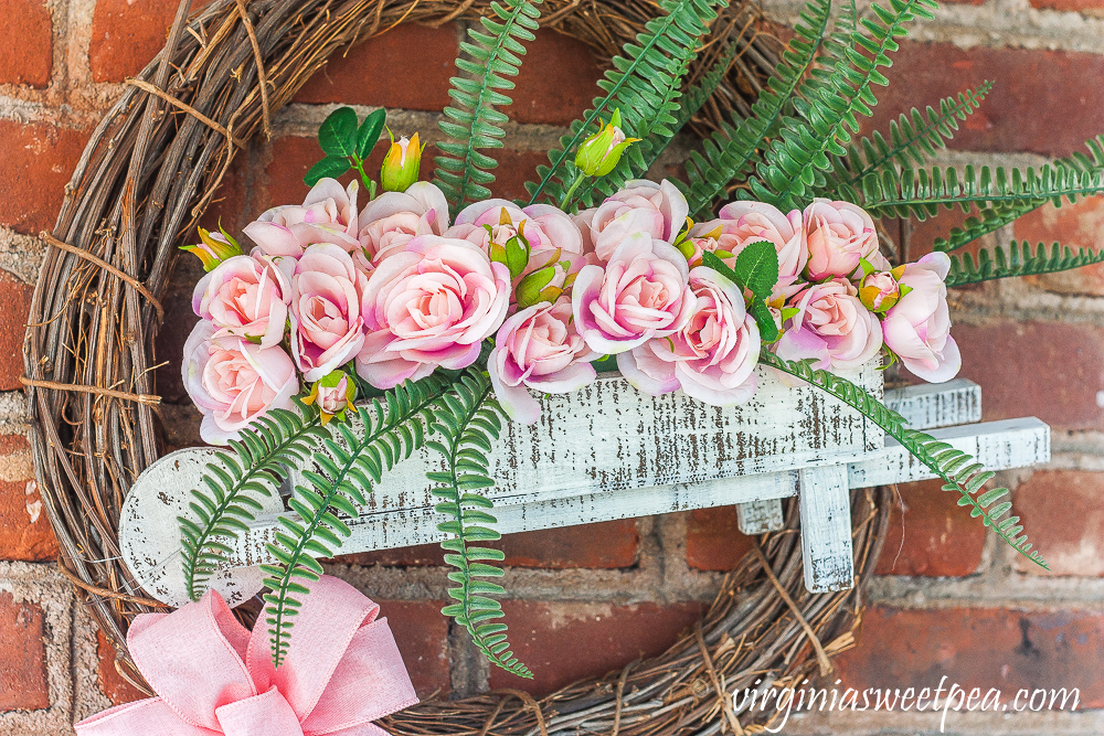 Spring wreath with a wheelbarrow filled with flowers