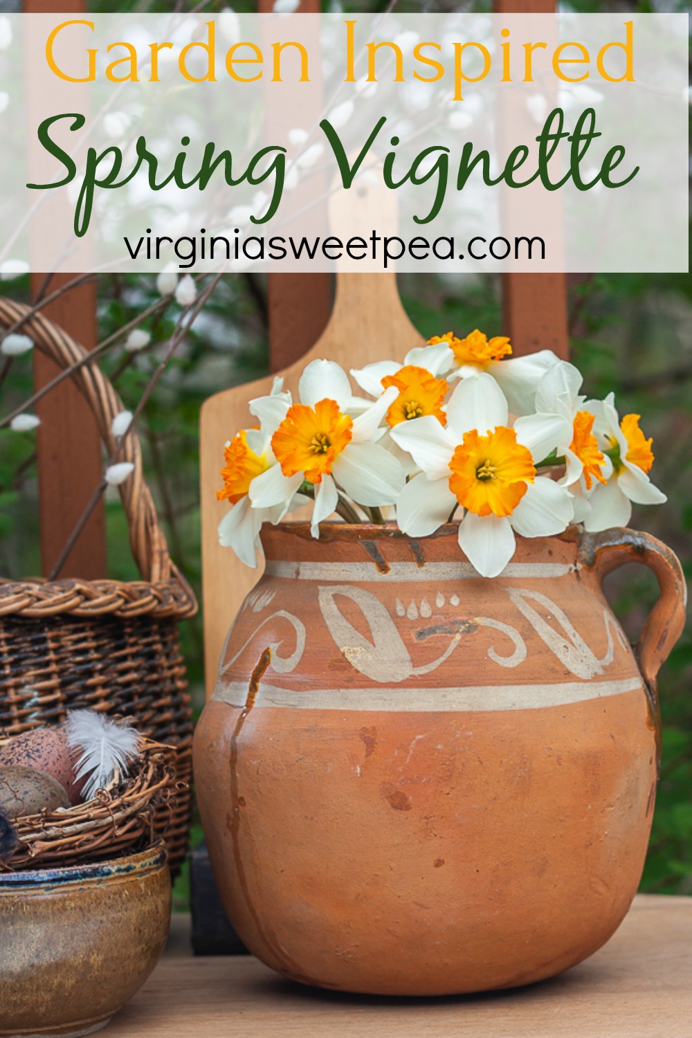 Spring vignette with an antique southerwestern pottery jug filled with daffodils, and antique basket, a pottery bowl holding a nest, and a wooden cutting board.