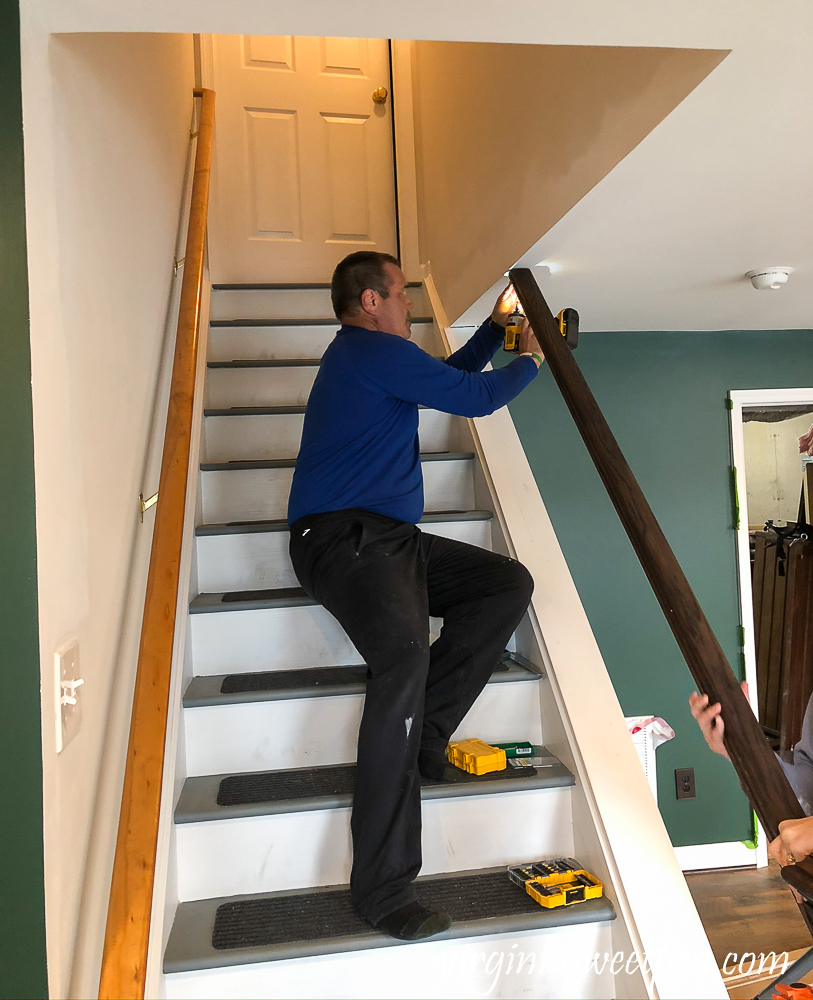 Screwing a banister to the ceiling on a staircase