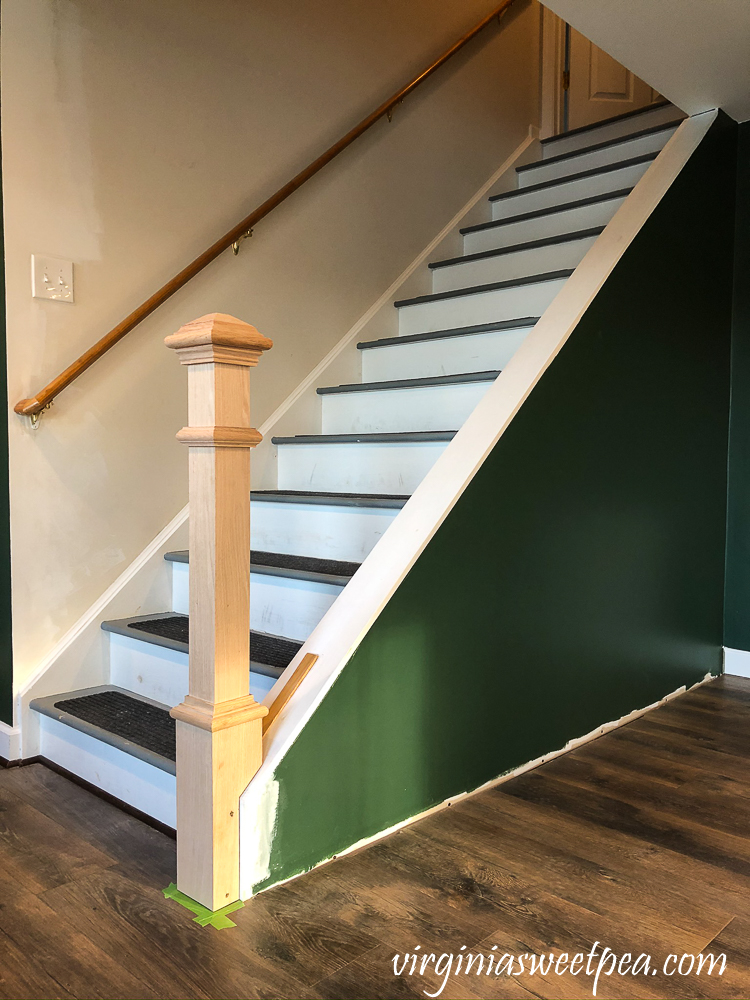 Newel post installed at the bottom of a set of stairs in a basement family room