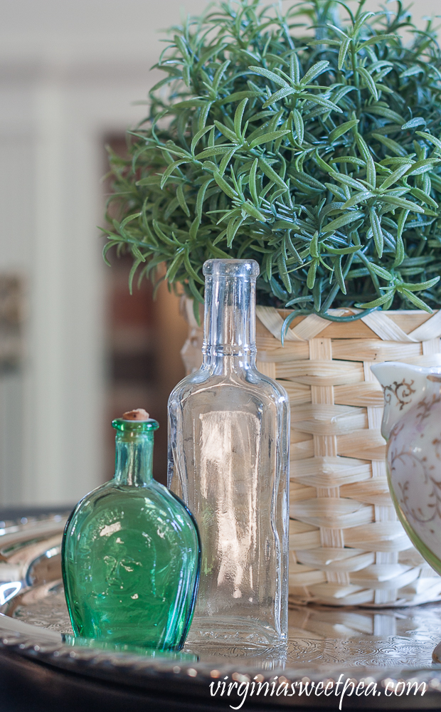 Spring Vignette with vintage bottles, vintage pitcher, and a faux rosemary plant in a basket