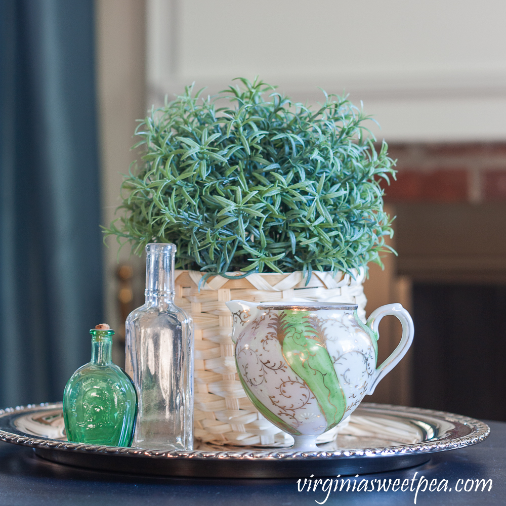 Spring Vignette with vintage bottles, vintage pitcher, and a faux rosemary plant in a basket