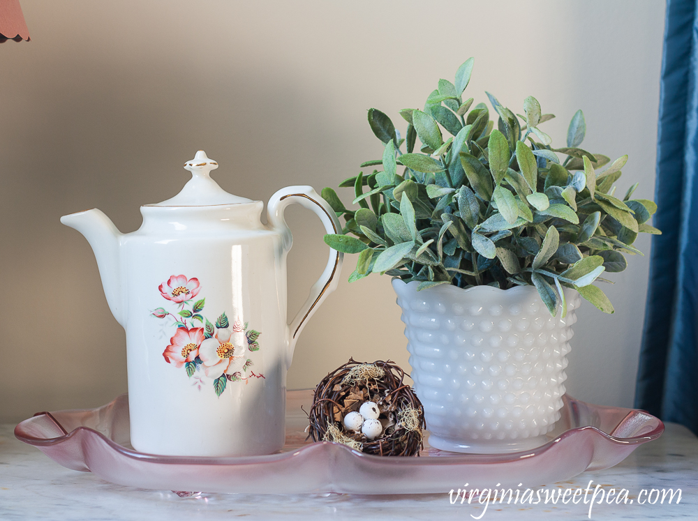 Spring Vignette with a bird nest, white pitcher with roses printed on the side and a faux plant in a milk glass hobnail vase