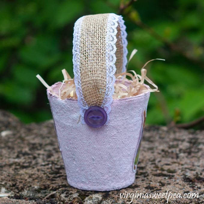 Easter treat basket made using a peat pot, ribbon, buttons, and an Easter sticker