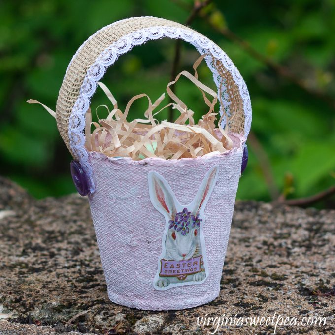 Easter treat basket made using a peat pot, ribbon, buttons, and an Easter sticker