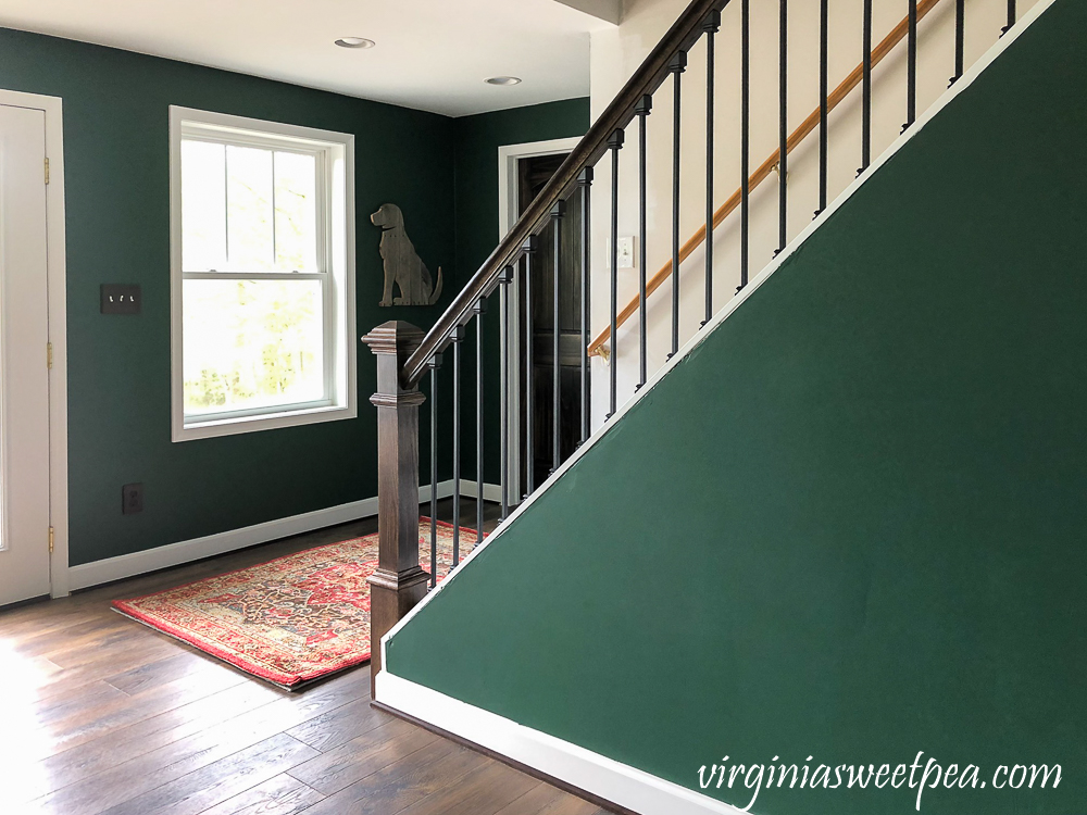 Staircase with metal balusters and a pallet wood dog on the wall