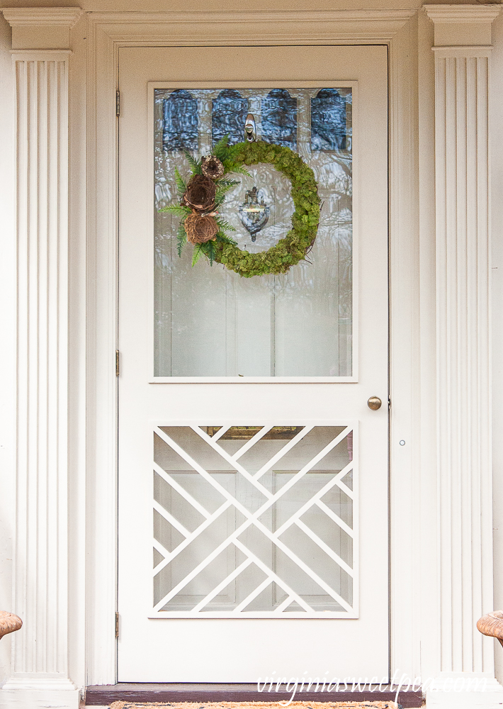 Chippendale door with a spring wreath covered in moss with birds nests and ferns on the side.