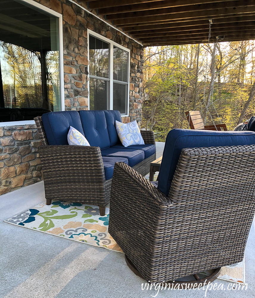 Patio at a lake house with sofa, chairs, and a porch swing.