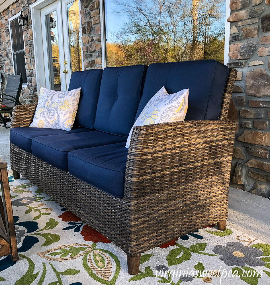 Patio at a lake house with a sofa, pillows, and a rug