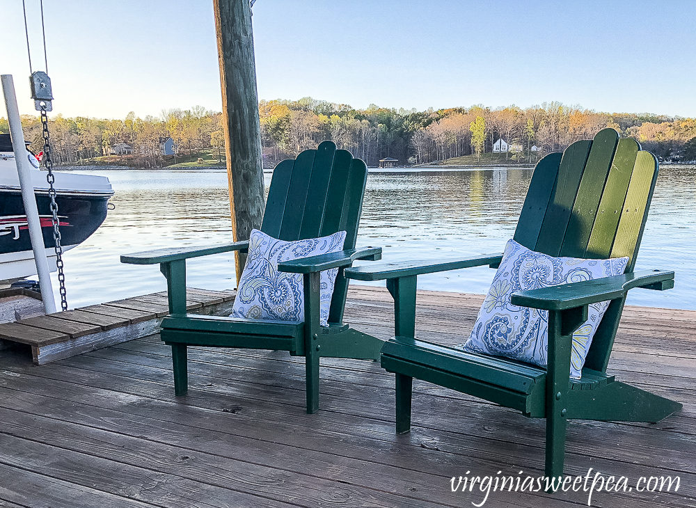 Two adirondack chairs on a dock with pillows