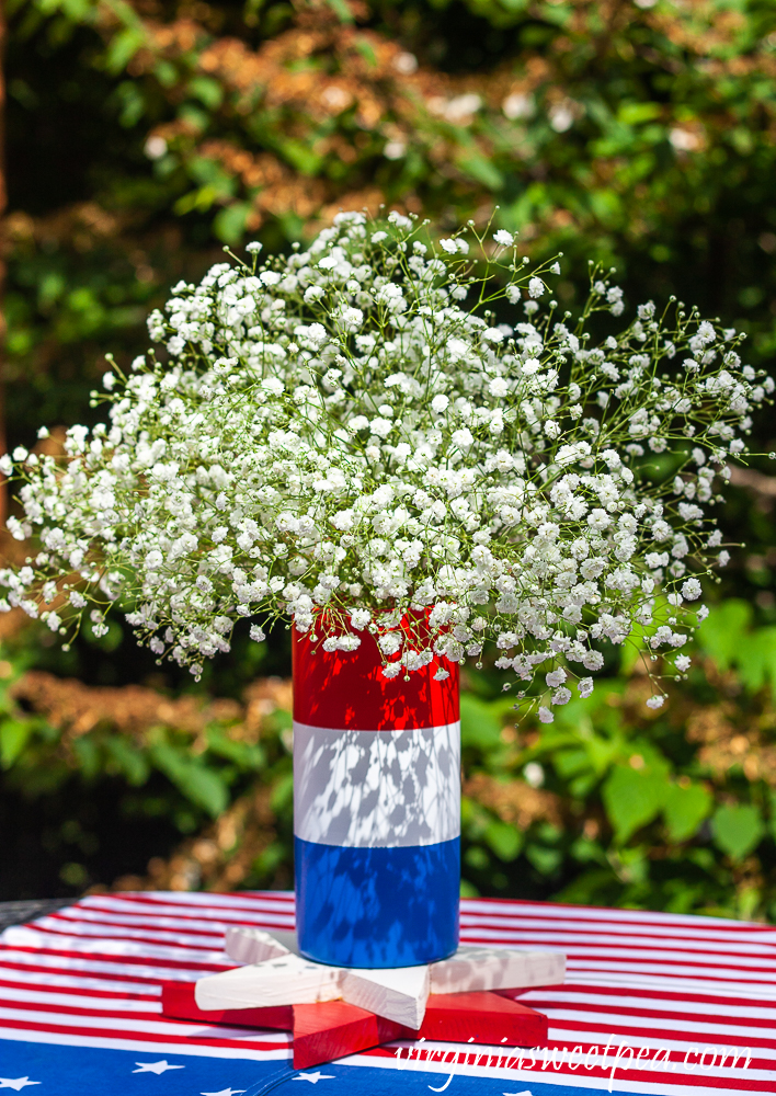 Red, white, and blue striped vase filled with Baby's Breath.