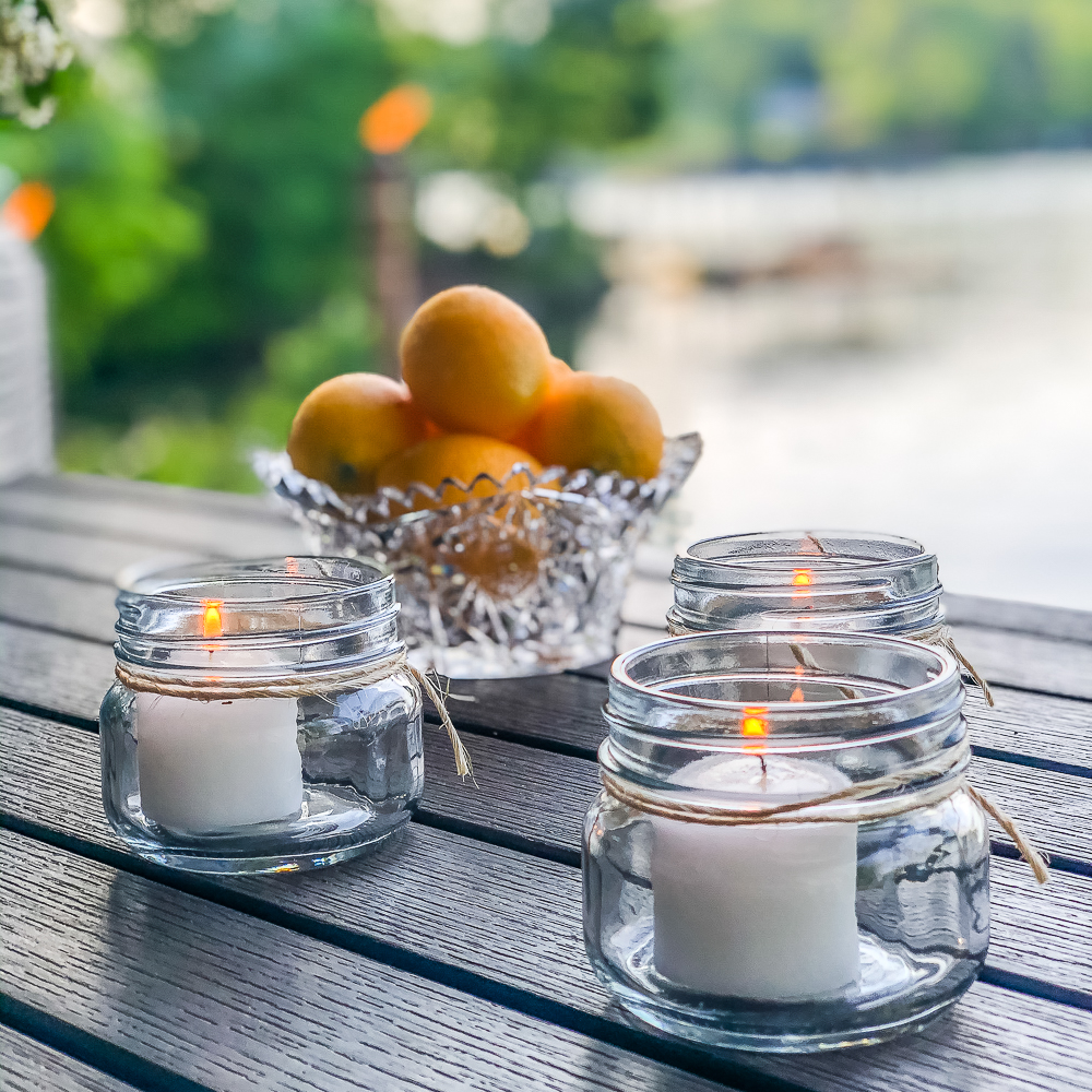 Candles in jars with twine tied around them and a bowl of lemons