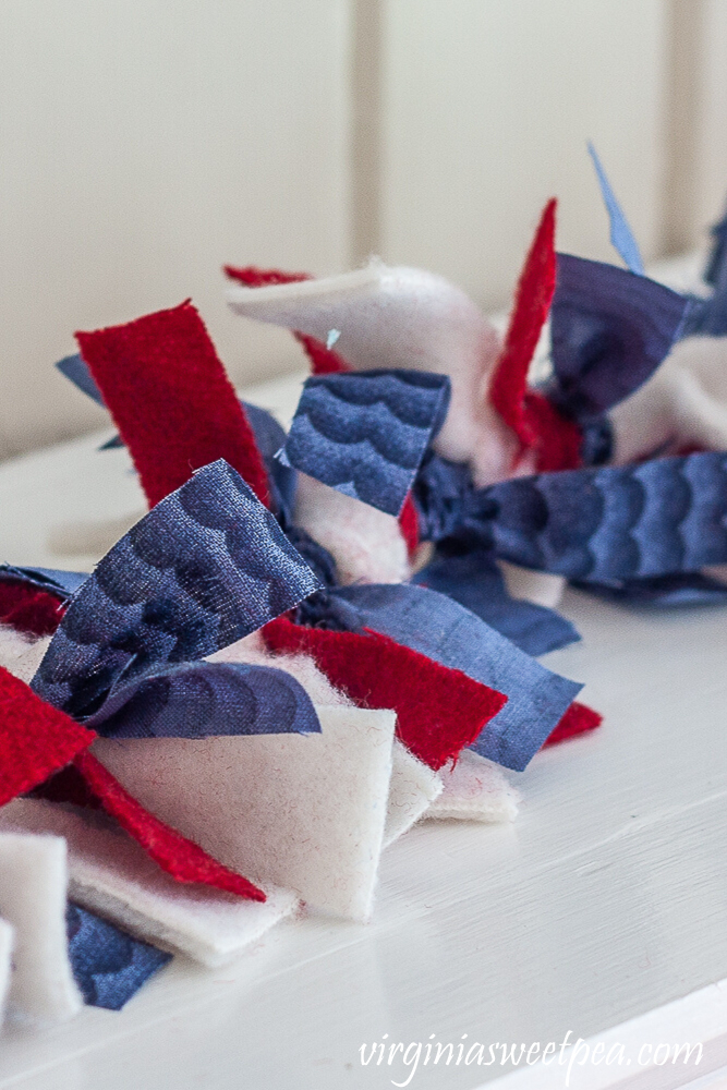 Garland made with strips of red, white, and blue fabric to decorate a mantel patriotically.