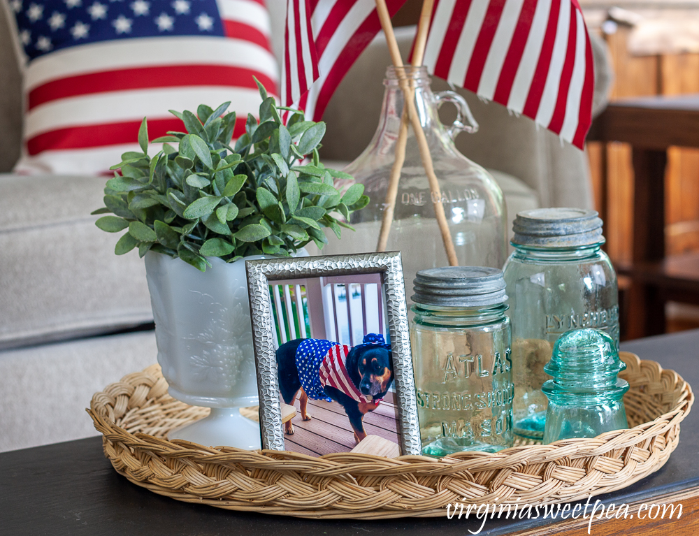 Patriotic Vignete with vintage Mason jars, vintage clear glass jug holding flags, and white milk glass compote with a faux plant