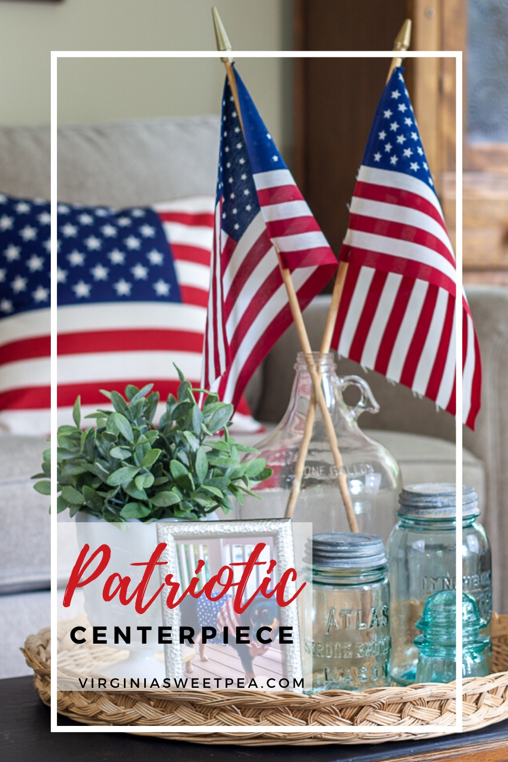 Patriotic Vignette with vintage Mason jars, vintage clear glass jug holding flags, and white milk glass compote with a faux plant and an American flag pillow in the background