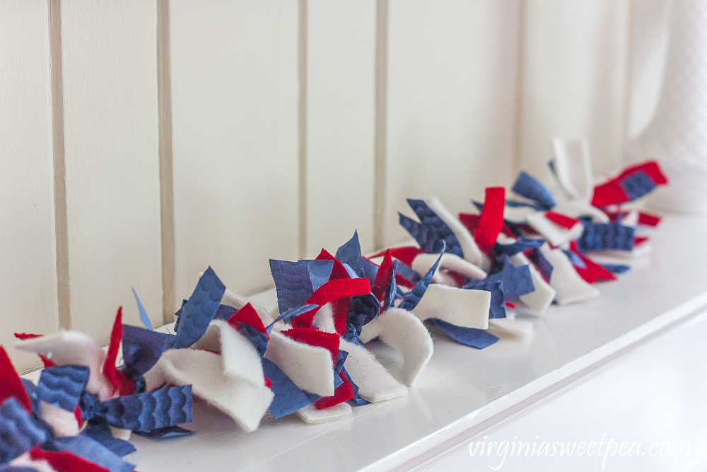 Rag garland made with red, white, and blue fabric strips, used on a mantel.