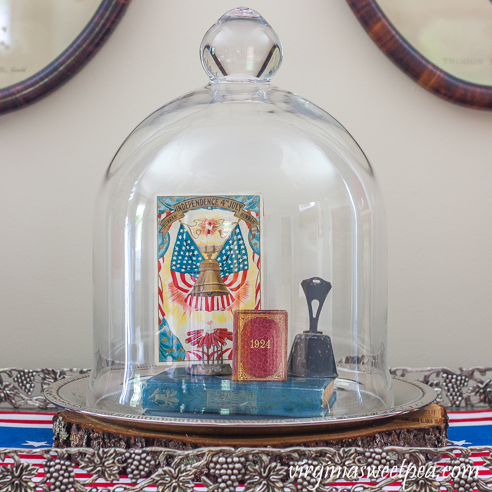 Cloche on a silver tray decorated with a Liberty Bell postcard, 1924 mini book, a vintage bell, and a vintage bible.