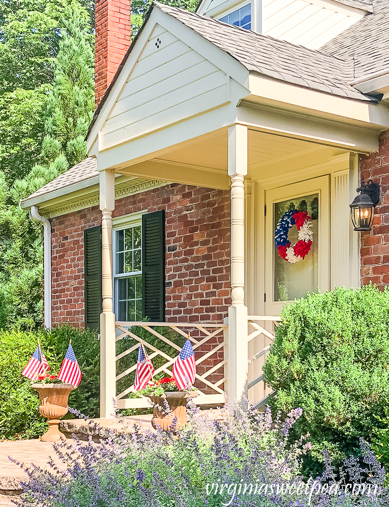 House decorated patriotically with red, white, and blue wreath and flags in flower pots.